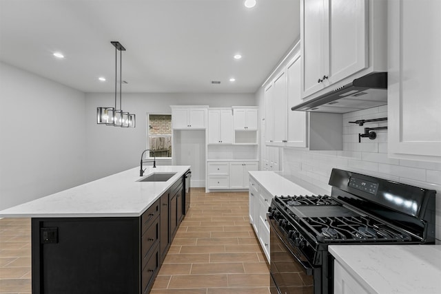 kitchen with gas stove, a sink, backsplash, white cabinetry, and under cabinet range hood
