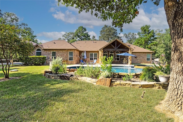 28116 Chuckwagon Trl, Magnolia, TX 77355 - rear view of property with an outdoor pool, a lawn, brick siding, and a patio