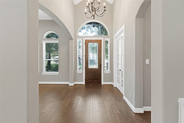28116 Chuckwagon Trl, Magnolia, TX 77355 - entrance foyer featuring arched walkways, a chandelier, dark wood finished floors, baseboards, and a towering ceiling