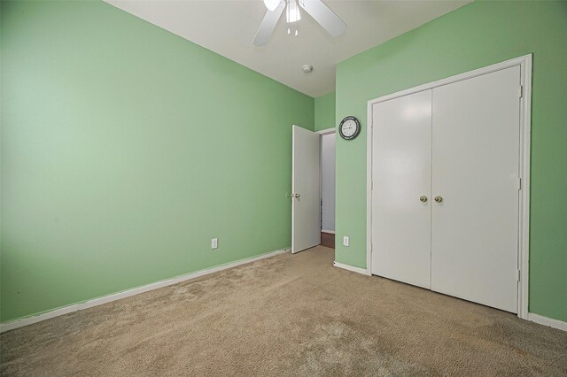 unfurnished bedroom featuring carpet flooring, baseboards, a closet, and a ceiling fan