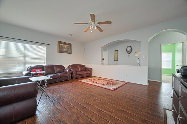 living area featuring hardwood / wood-style floors, ceiling fan, and arched walkways
