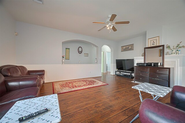 living room featuring hardwood / wood-style flooring, ceiling fan, and arched walkways