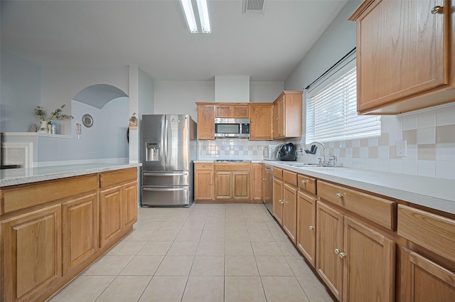 kitchen with stainless steel appliances, a sink, light countertops, and decorative backsplash