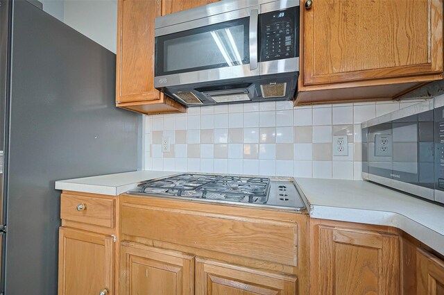 kitchen with stainless steel appliances, light countertops, and tasteful backsplash