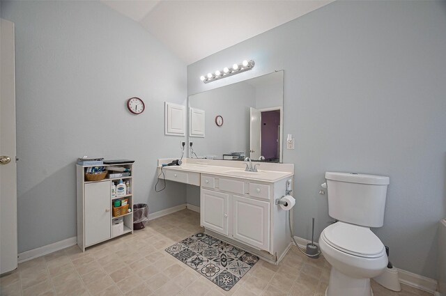 bathroom featuring lofted ceiling, vanity, toilet, and baseboards
