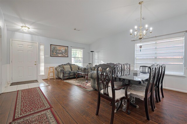 dining area with a chandelier, wood finished floors, vaulted ceiling, and baseboards