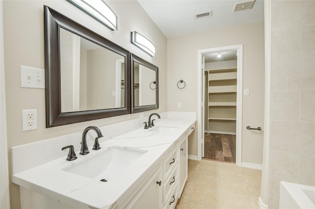 9024 Zapata Way, Willis, TX 77378 - full bathroom with double vanity, tile patterned floors, a tub, a spacious closet, and baseboards