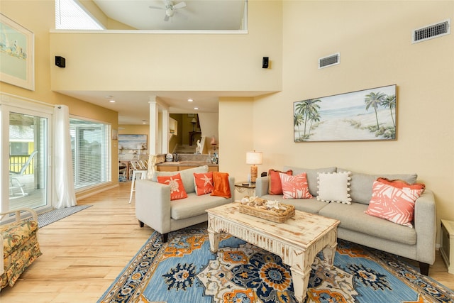 living area with a high ceiling, light wood finished floors, healthy amount of natural light, and a ceiling fan