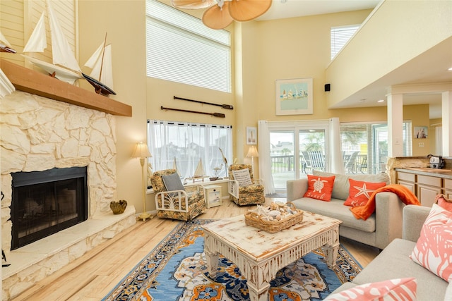 living area featuring wood finished floors, a high ceiling, a fireplace, and ceiling fan