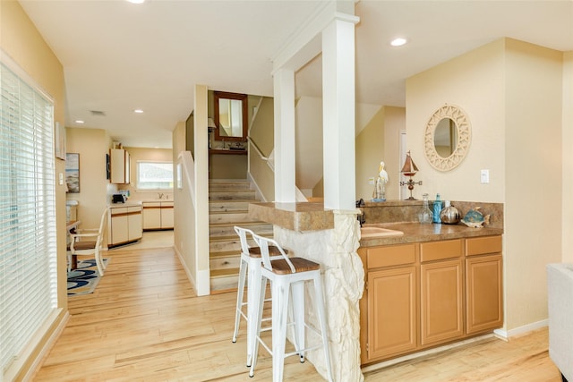 indoor wet bar featuring light wood finished floors, stairs, recessed lighting, and baseboards