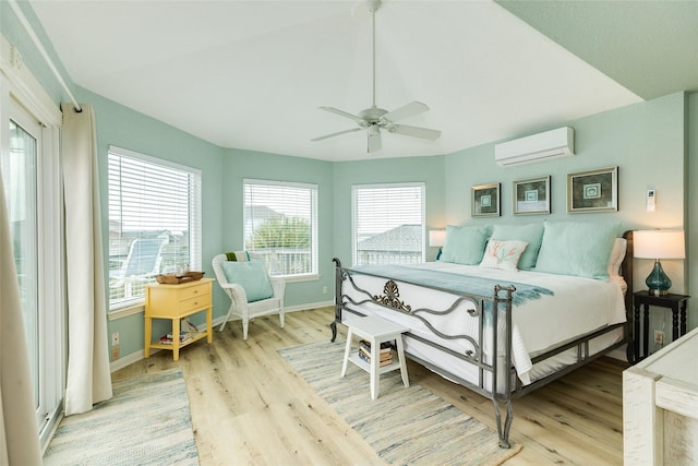 bedroom with an AC wall unit, light wood-style flooring, baseboards, and vaulted ceiling