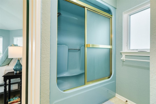 bathroom with baseboards, a textured wall, and bathtub / shower combination