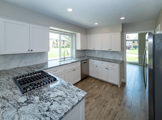 2414 Shoal Creek Dr, League City, TX 77573 - kitchen featuring stainless steel appliances, a sink, light stone countertops, decorative backsplash, and white cabinets