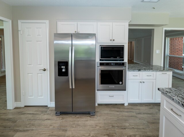 2414 Shoal Creek Dr, League City, TX 77573 - kitchen featuring stainless steel appliances, light wood-type flooring, light stone countertops, and white cabinets