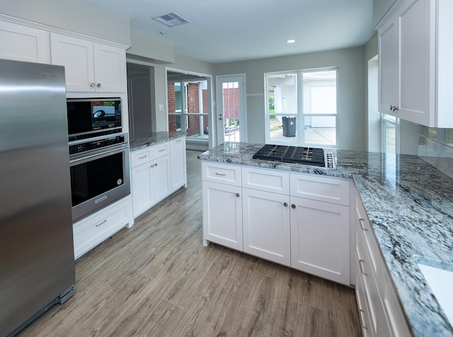 2414 Shoal Creek Dr, League City, TX 77573 - kitchen featuring appliances with stainless steel finishes, white cabinetry, light wood finished floors, light stone countertops, and recessed lighting