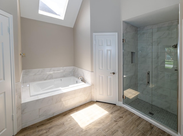 2414 Shoal Creek Dr, League City, TX 77573 - bathroom featuring a skylight, wood finished floors, vaulted ceiling, a bath, and a stall shower