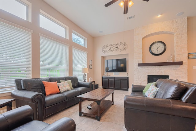12607 Cove Landing Dr, Cypress, TX 77433 - living room with light tile patterned flooring, ceiling fan, a towering ceiling, and a stone fireplace