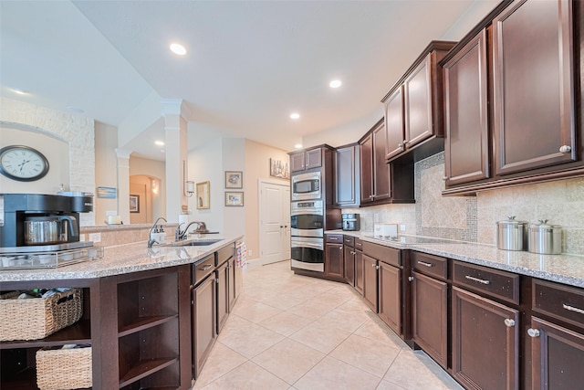 12607 Cove Landing Dr, Cypress, TX 77433 - kitchen with decorative columns, a sink, open shelves, light tile patterned flooring, and stainless steel microwave
