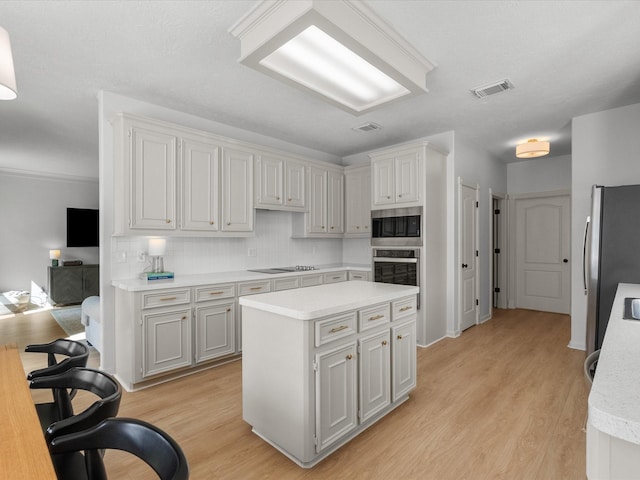 kitchen with appliances with stainless steel finishes, light countertops, tasteful backsplash, and light wood-type flooring