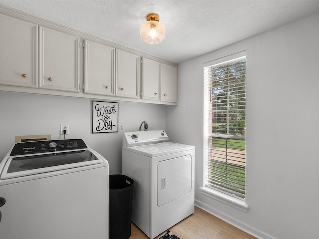 washroom with washer and clothes dryer, cabinet space, light wood finished floors, and baseboards