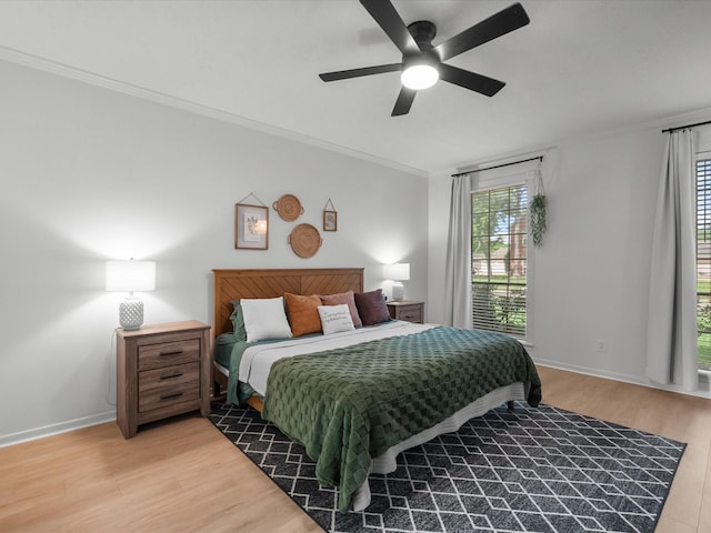 bedroom featuring ornamental molding, light wood-type flooring, ceiling fan, and baseboards