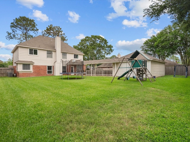 rear view of house with a trampoline, a playground, a chimney, central air condition unit, and brick siding