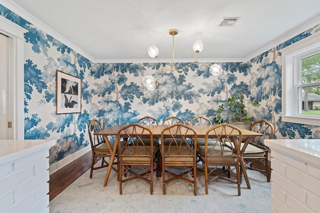 dining space featuring wood finished floors, wallpapered walls, crown molding, and baseboards