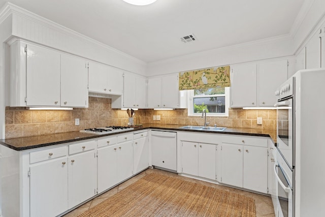 kitchen featuring a sink, white appliances, decorative backsplash, white cabinetry, and ornamental molding