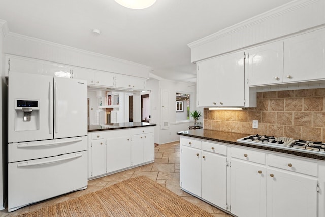 kitchen with white appliances, dark countertops, white cabinets, ornamental molding, and tasteful backsplash