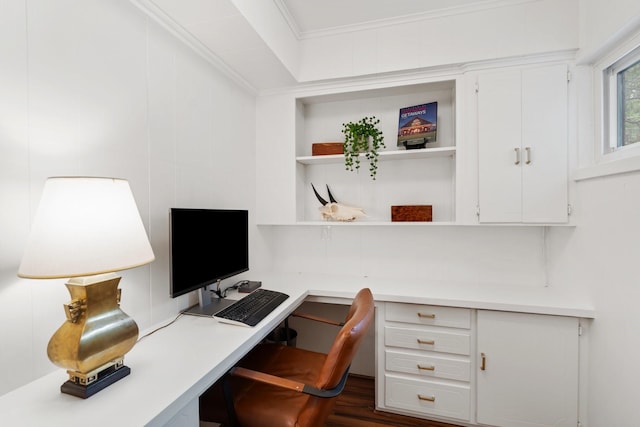office area with built in study area, crown molding, and dark wood finished floors