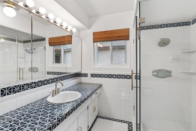 bathroom with a shower stall, tile walls, tile patterned flooring, and vanity