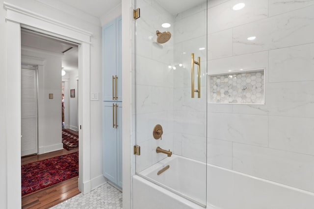 bathroom featuring washtub / shower combination, baseboards, and wood finished floors