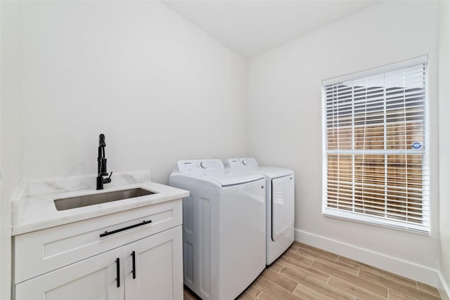 1003 Kelley St, Houston, TX 77009 - laundry area featuring washing machine and dryer, light wood finished floors, cabinet space, and baseboards