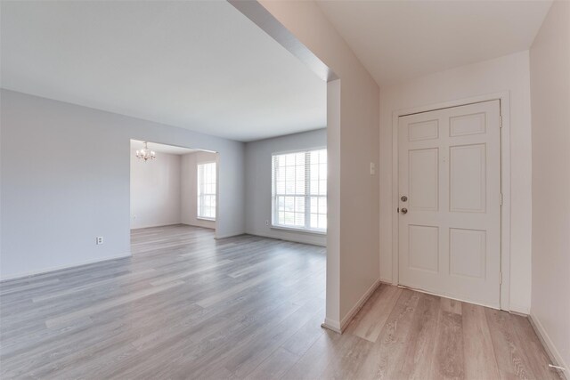 entrance foyer with a chandelier, light wood finished floors, and baseboards