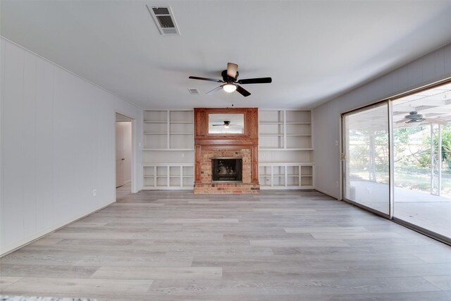 unfurnished living room featuring ceiling fan, light wood-style floors, and built in shelves