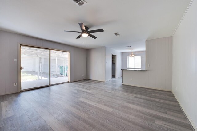 unfurnished living room featuring ceiling fan, baseboards, light wood-style flooring, and a chandelier