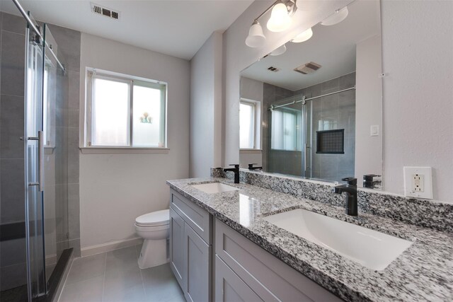 bathroom featuring a stall shower, toilet, tile patterned flooring, double vanity, and baseboards