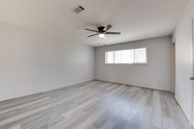 empty room with light wood finished floors, a ceiling fan, and baseboards
