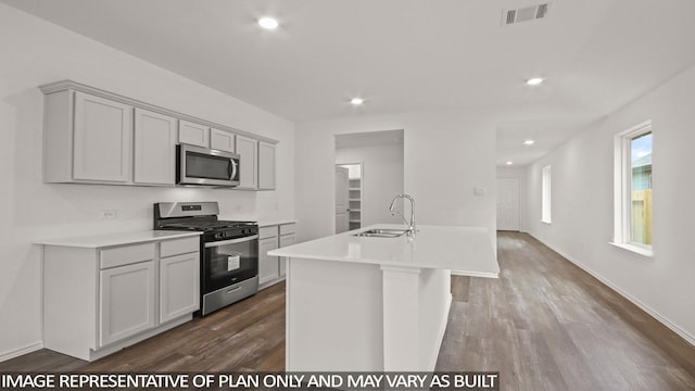 1346 Heather Rosewood Ln, Conroe, TX 77301 - kitchen featuring stainless steel appliances, a sink, dark wood-style flooring, a center island with sink, and light countertops