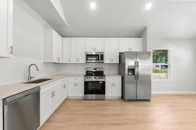 kitchen featuring appliances with stainless steel finishes, a sink, white cabinets, light countertops, and recessed lighting