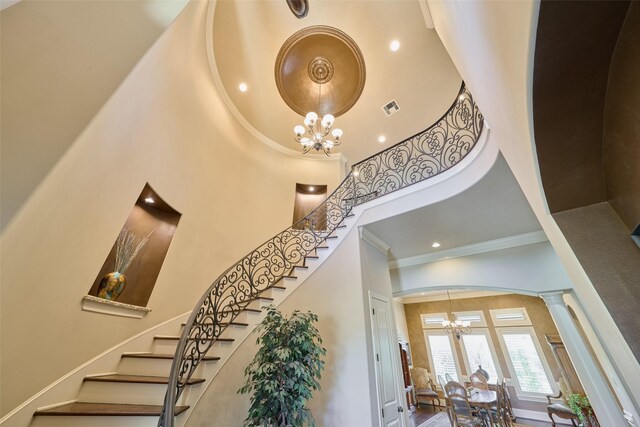 entryway featuring a chandelier, a towering ceiling, ornamental molding, stairway, and recessed lighting
