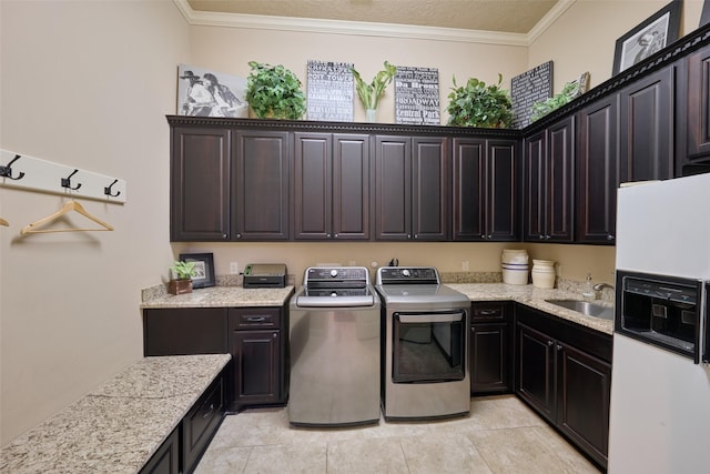 laundry area with cabinet space, separate washer and dryer, ornamental molding, and light tile patterned flooring