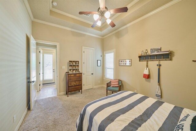 bedroom featuring multiple windows, carpet, a tray ceiling, crown molding, and a ceiling fan