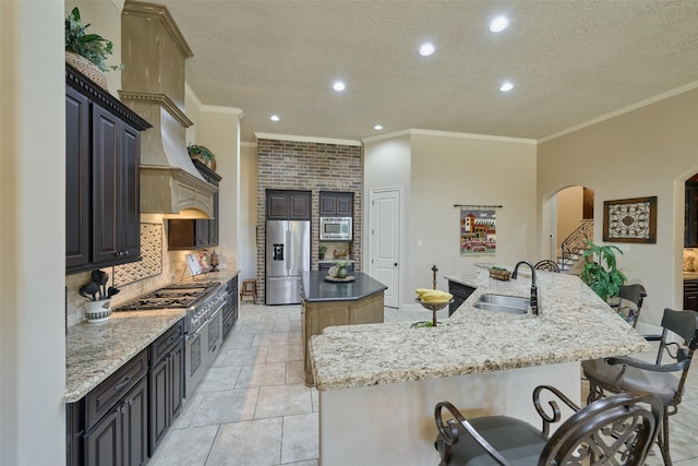 kitchen with stainless steel appliances, a large island, a sink, arched walkways, and backsplash