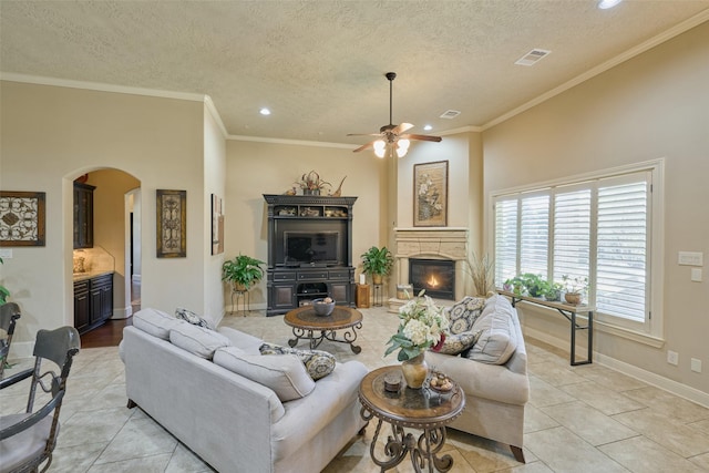 living area with arched walkways, a ceiling fan, recessed lighting, a textured ceiling, and light tile patterned flooring