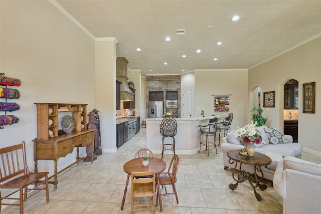 living area with recessed lighting, ornamental molding, arched walkways, light tile patterned flooring, and baseboards