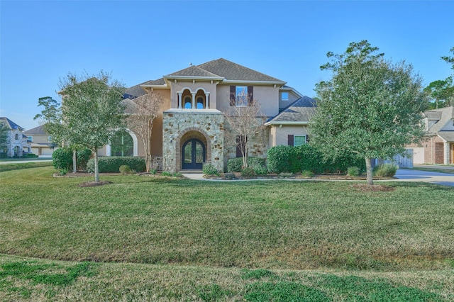 mediterranean / spanish-style home featuring french doors, stucco siding, stone siding, and a front lawn
