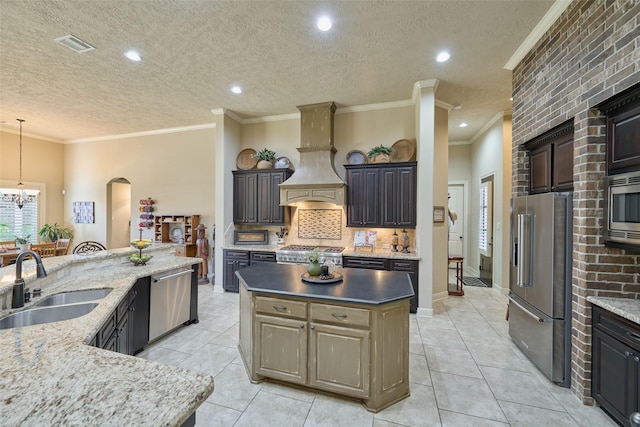 kitchen with stainless steel appliances, a sink, a kitchen island, premium range hood, and a chandelier
