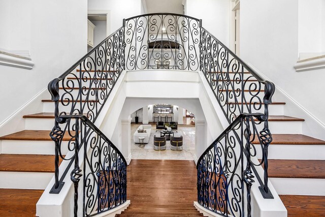 5105 Pocahontas St, Bellaire, TX 77401 - staircase featuring arched walkways, a towering ceiling, and wood finished floors
