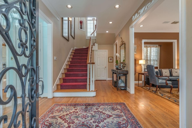 entryway featuring wood finished floors, crown molding, stairway, recessed lighting, and baseboards